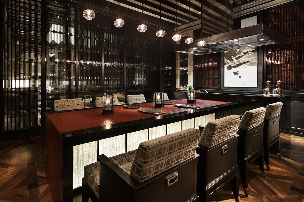 Modern restaurant interior with dark wood tables and chairs, ambient lighting, and decorative elements.