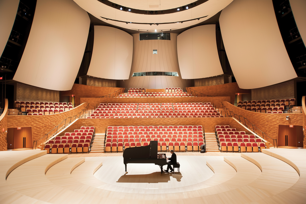 Large auditorium with red seats and a piano on a stage