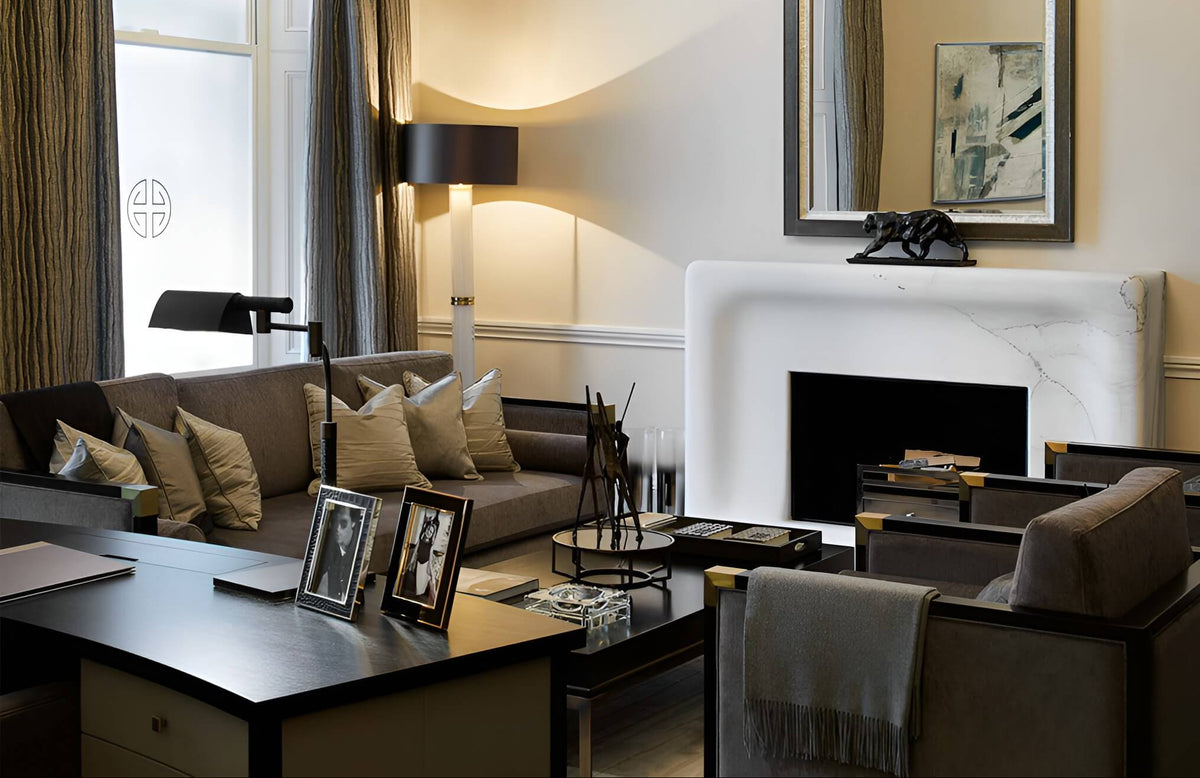 A styled living room interior featuring a brown upholstered sofa with beige pillows, a dark wood coffee table, a white fireplace mantel, and a large mirror on the wall.