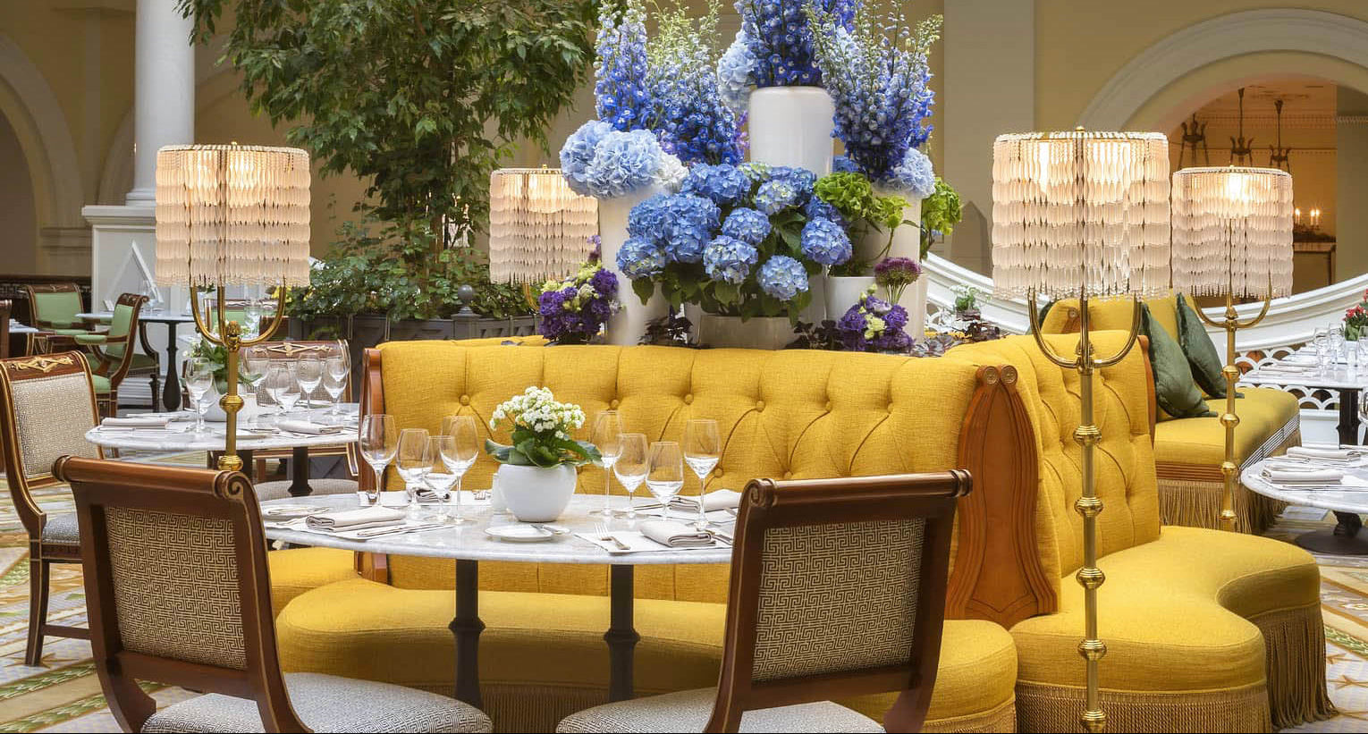 Luxurious interior with a yellow sofa, decorative flowers, and elegant table setting.