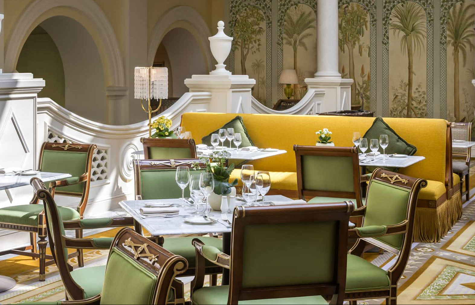 Elegant restaurant interior with yellow booth and green chairs.