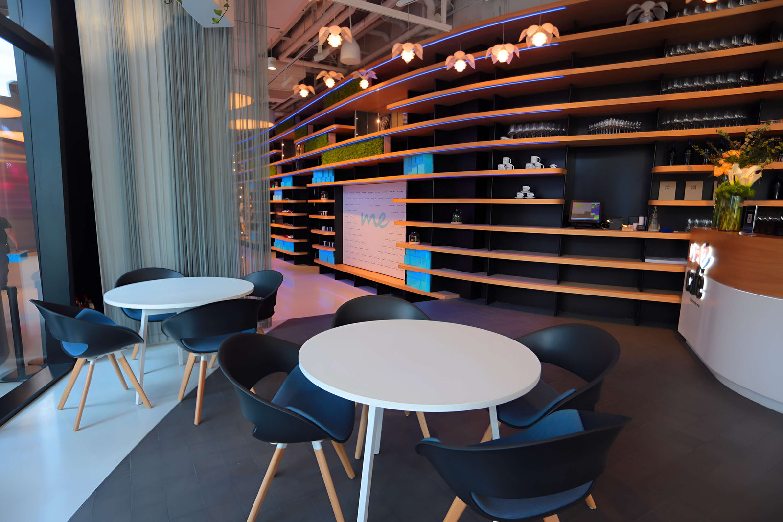 Modern interior with round tables and black chairs in a room with shelves and decorative elements.