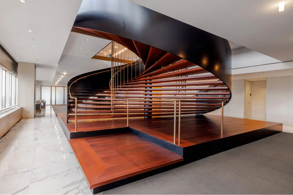 Modern staircase with wooden steps and black handrail in a well-lit interior setting