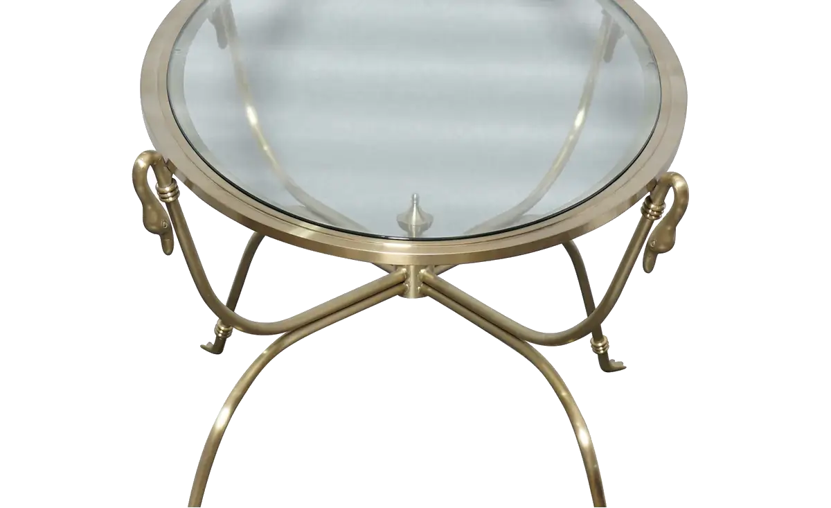 A round glass-top side table with a polished brass or gold-finished metal frame and decorative scroll legs, shown on a plain white background.