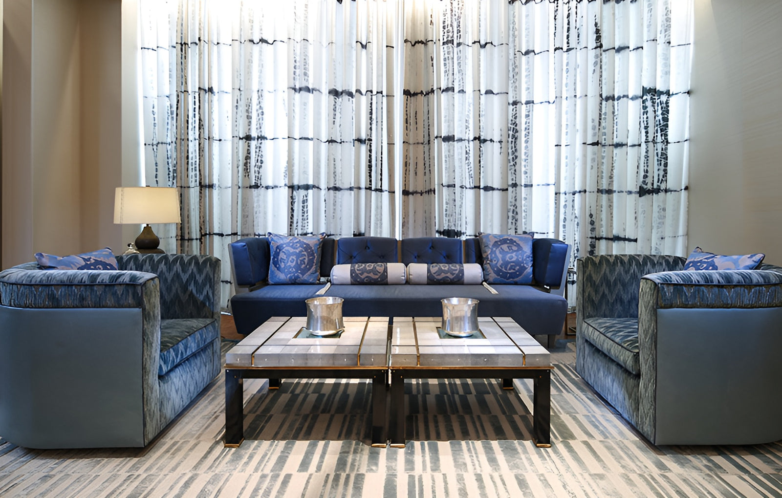 Modern living room with blue and gray furniture and patterned curtains.