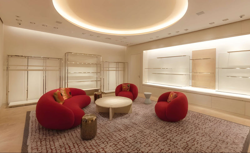 Modern living room with red sofas, a round coffee table, and decorative pillows.