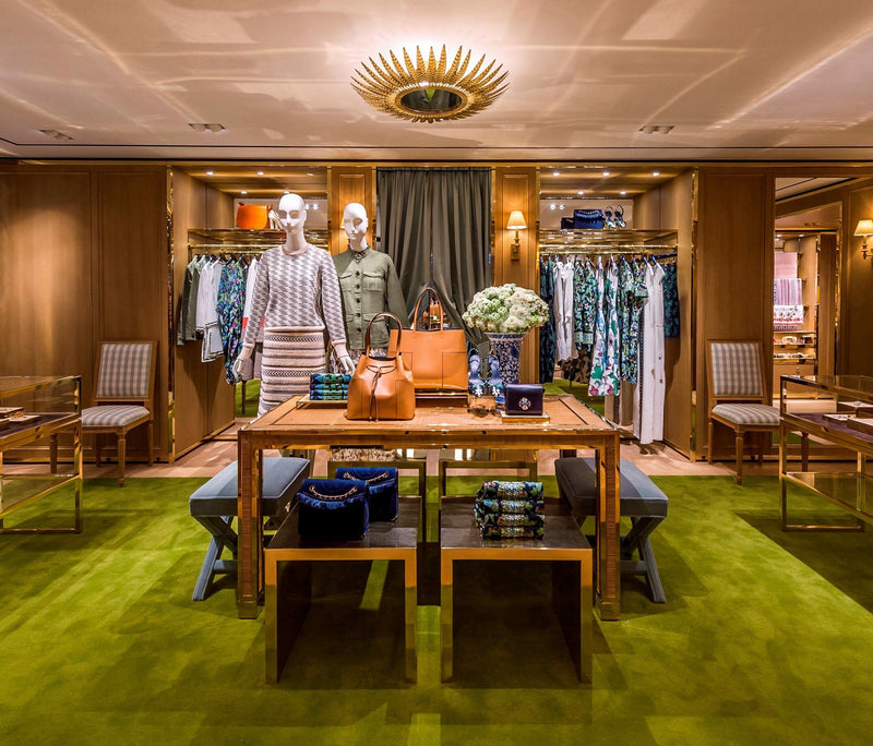 Interior of a high-end clothing store with display tables and chairs.